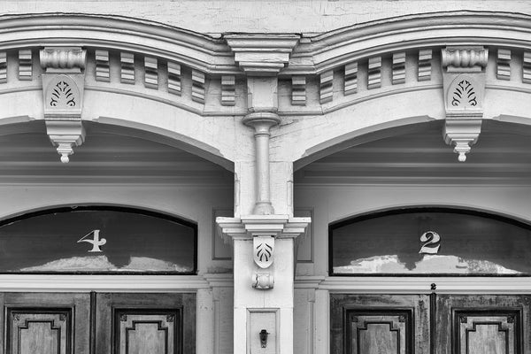 Black and white architectural detail photograph of a two numbered doors in a historic old building.