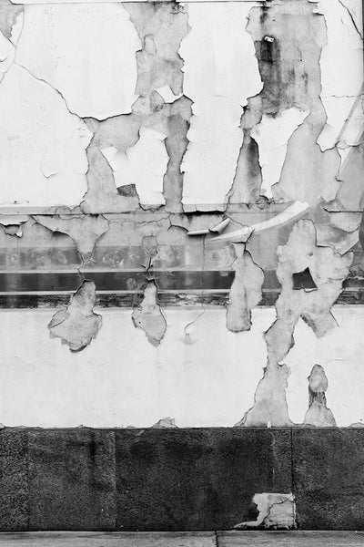 Black and white photograph of a downtown wall with paint and mural fragments peeling away in a beautifully random way.