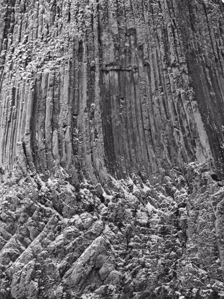 Black and white detail photograph of the face of Devil's Tower, with a light frosting of snow.