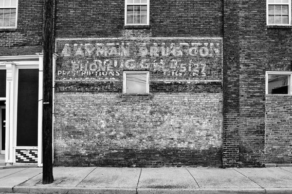 Black and white photograph of the side of an old pharmacy building in the Chestnut Hill neighborhood of Nashville, with a fading painted sign that reads "Layman Drug Co."
