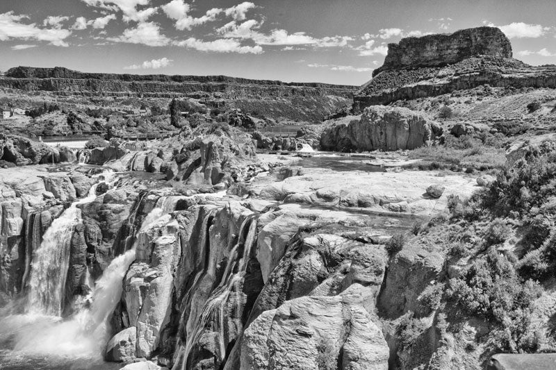 Black and white photograph of the Idaho landscape with a mesa in the background and two waterfalls in the foreground.