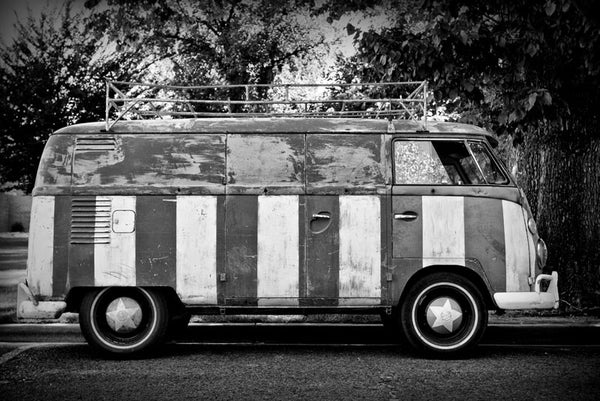 Black and white photograph of a vintage VW van that's been hand-painted top-to-bottom with a giant US flag.