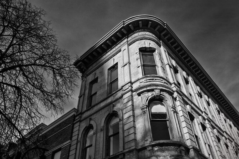 Black and white photograph of a historic building on the corner of the downtown square in Madison, Wisconsin, just catching the low light of the winter sun.