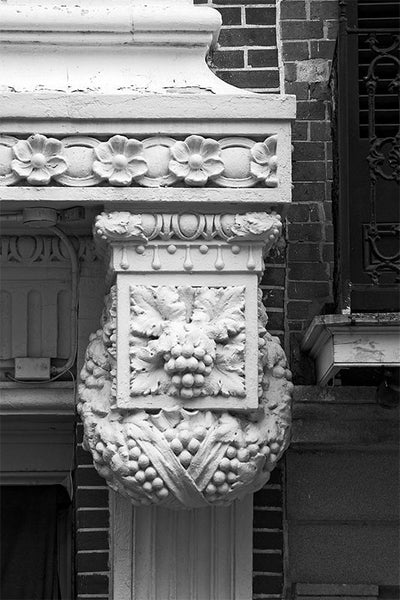 Black and white architectural detail photograph of decorative metalwork with a grape cluster and floral motif in New Orleans.