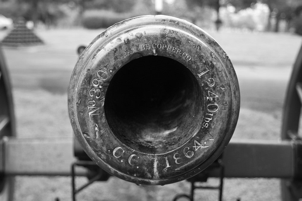 Black and white photograph of the muzzle of a civil war cannon at Stones River National Military Cemetery in Murfreesboro, Tennessee. The engraving reads "No. 390. Revere Copper Co. 1240 lbs. C.C. 1864."