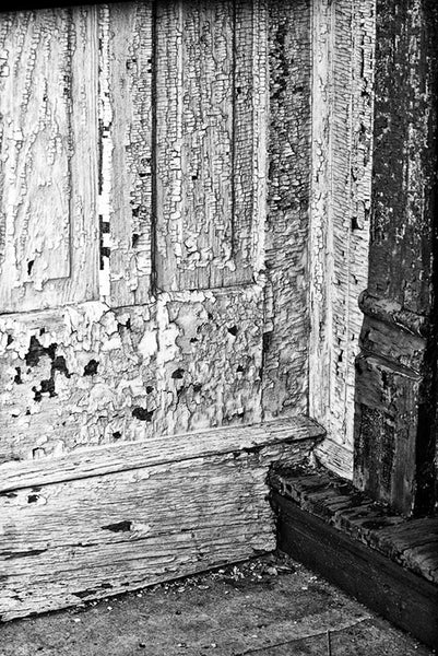Black and white photograph of peeling paint on an abandoned building in a small town that was once adapted by one of the many groups in the late 1800s who sought to create a perfect society under utopian ideals.