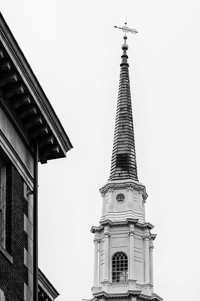 Black and white architectural photograph of a historic church steeple towering above the city
