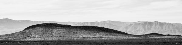 Black and white panoramic landscape photograph of layers of rugged West Texas mountains.