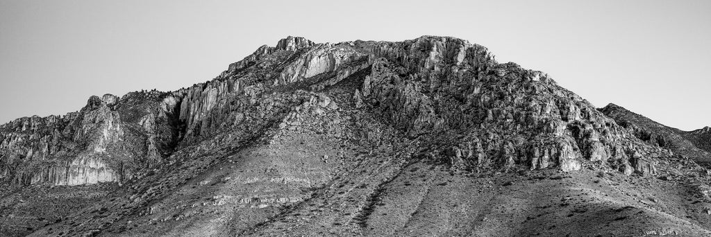 Black and white panoramic landscape photograph of the massive, rugged, and rocky peaks of the Guadalupe Mountains.