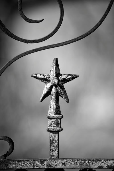 Black and white photograph of a star finial on an old fence surrounding an abandoned old house in far West Texas.