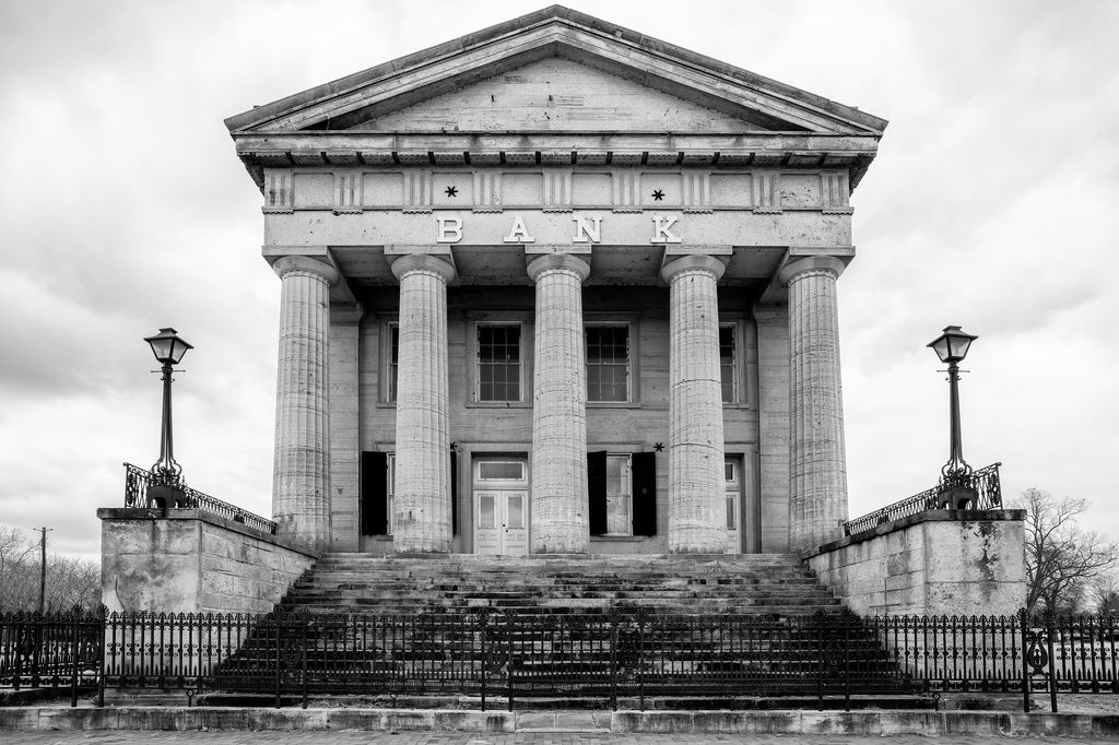 Black and white photograph of the front elevation of the big historic abandoned bank in Old Shawneetown, Illinois. Built between 1839 -1841, it's the oldest bank building in the state, and legend says the bank once declined to buy the first bonds issued by the city of Chicago, thinking the city had no future.