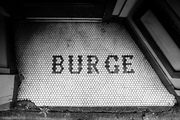 Black and white photograph of the custom tile entry to a business that was once owned by someone named "Burge" in a building constructed in 1915.