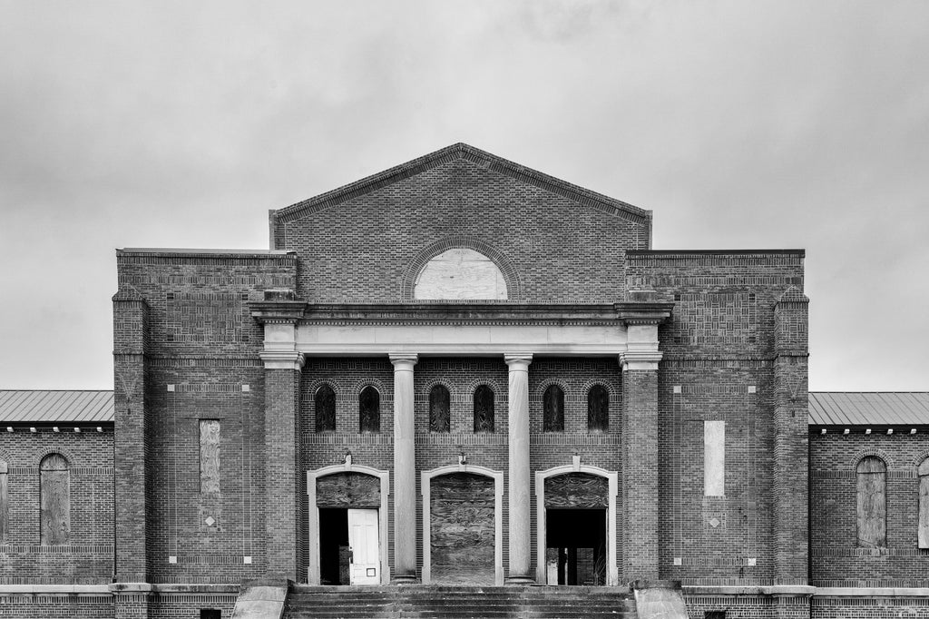 Black and white photograph of a majestic but abandoned building on a vacant college campus in the American South.