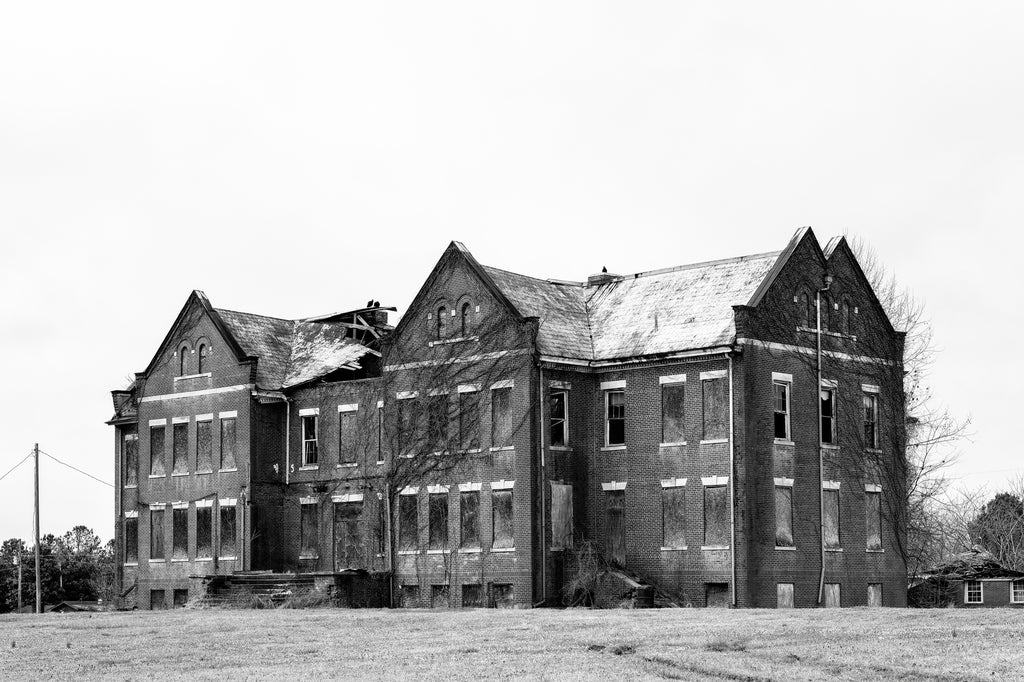 Black and white photograph of a large derelict building on a completely abandoned college campus in the American South.