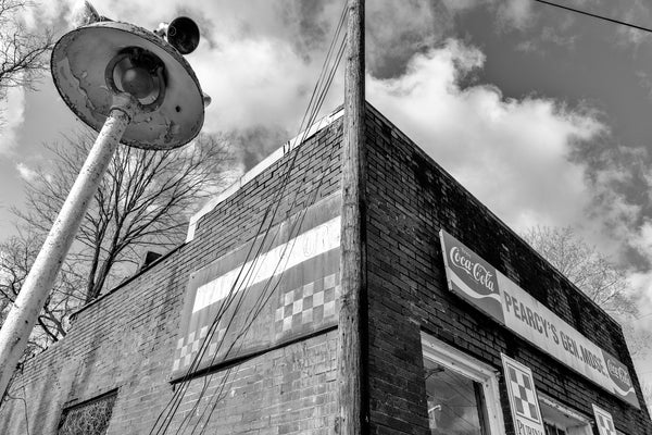Black and white photograph of vintage signs on the exterior of an abandoned old country store.