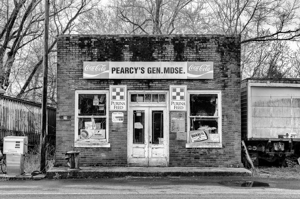 Black and white photograph of an abandoned country store with vintage ads on its exterior.