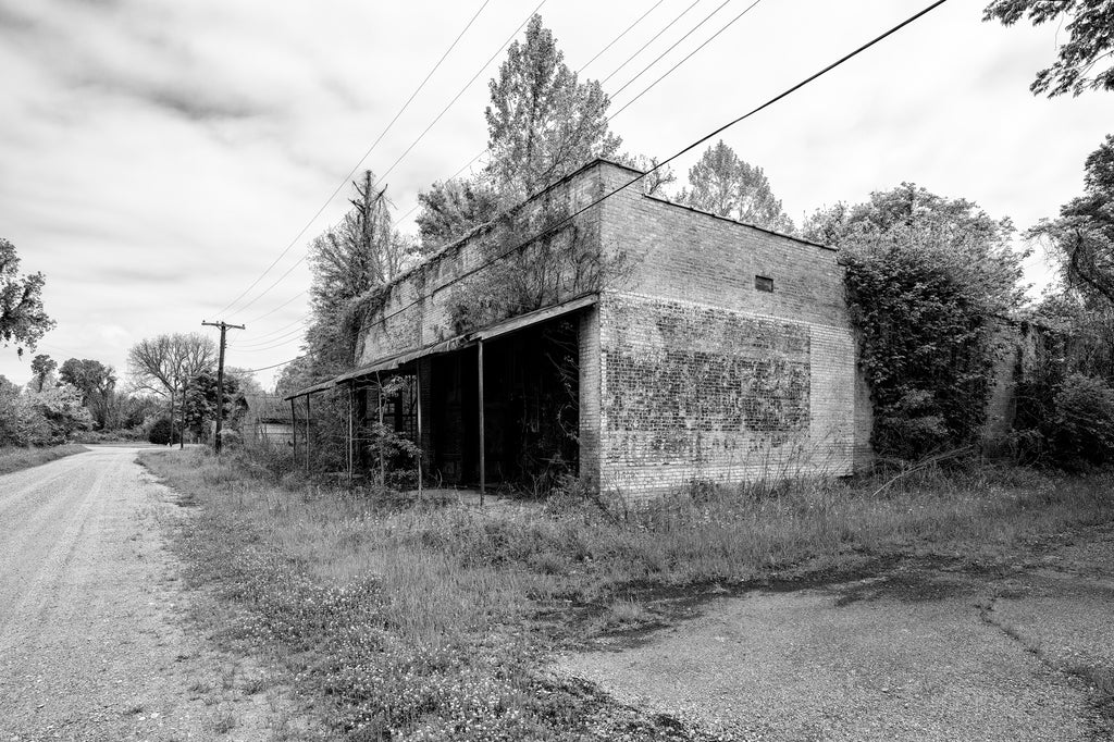 Black and white photograph of abandoned storefronts now in ruins in the small Mississippi Delta community of Hushpuckena.