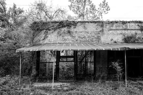 Black and white photograph of abandoned storefronts now in ruins in the small Mississippi Delta community of Hushpuckena.