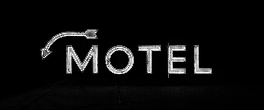 Black and white photograph of a vintage neon sign for an old roadside motel featuring an arrow pointing downward.