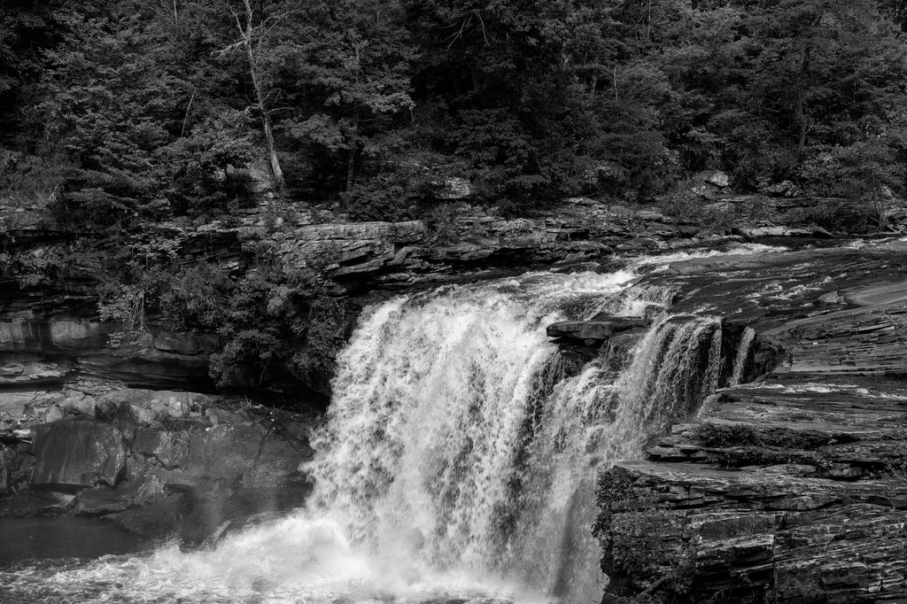 Black and white landscape photograph of Little River Canyon Falls crashing over a rocky ledge into the river below.