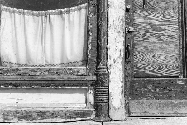 Black and white photograph of an abandoned building with white curtains at 3600 Jacob Street in Wheeling, West Virginia that opened as a merchant tailor shop owned by August Helmbrecht in 1891.