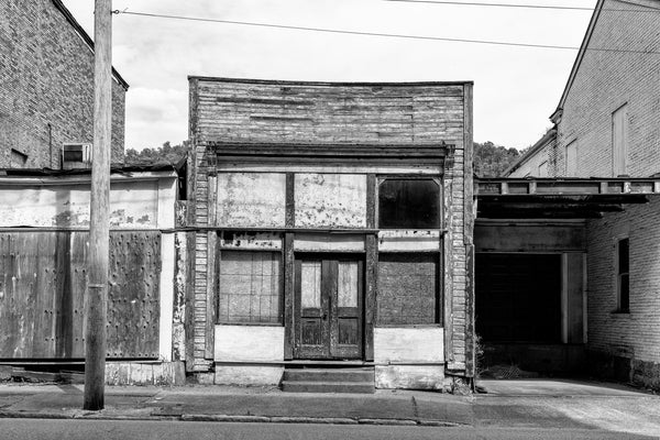 Black and white photograph of an abandoned wooden building, circa 1891, that was a house and sign painting business owned by Charles Seybold in South Wheeling, West Virginia.