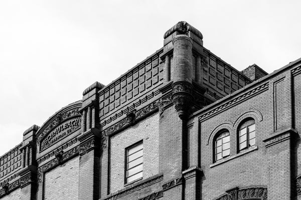 Black and white photograph of architectural details on the exterior of the historic Schmulbach Brewing Company. Founded as the Nail City Brewery in 1855, it was acquired by investors in 1873. Majority partner Henry Schmulbach changed the name in 1882. This structure was built in 1891, and Schmulbach was closed in 1914 when West Virginia passed prohibition laws.