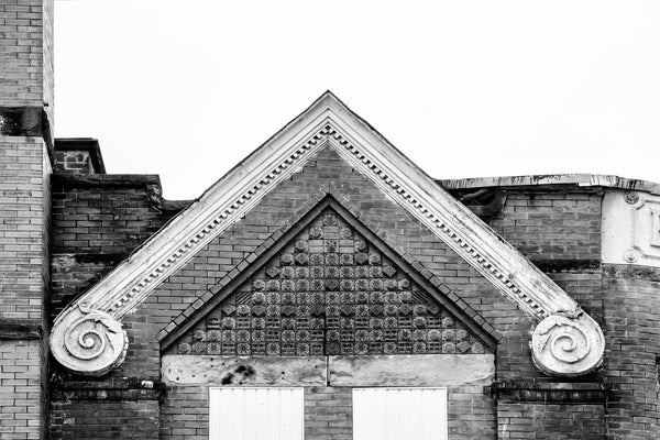 Black and white architectural detail photograph of a checkerboard pattern of ornate tiles on the apex roofline of an old commercial storefront in Moundsville, West Virginia.
