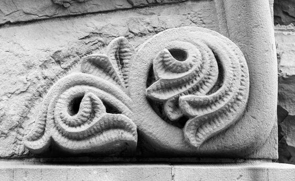 Black and white photograph of a beautifully carved stone ornament on an old building in downtown Rochester, New York.