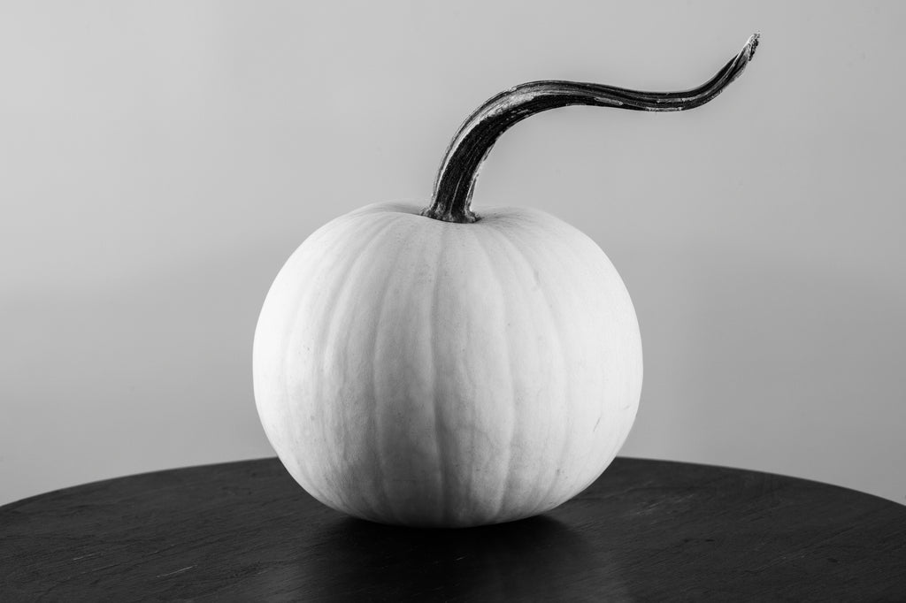 Black and white photograph of a white pumpkin with an elegantly curved stem.