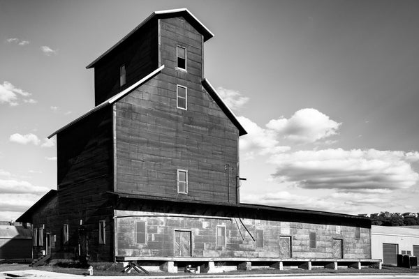 Black and white photograph of a historic grain elevator with corrugated metal siding.