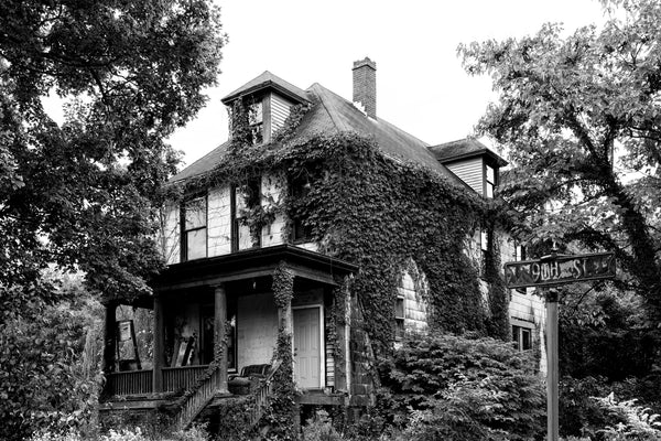 Black and white photograph of a big, abandoned house covered in ivy at 9th and Cedar Street in Cairo, Illinois.