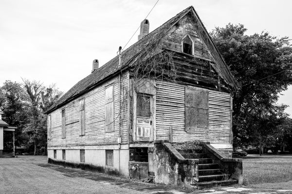 Black and white photograph of a large, wooden shotgun house at 1102 Poplar Street in Cairo, Illinois. The history of the structure is unclear. It may have been a residence but could have also been a church or a commercial building.