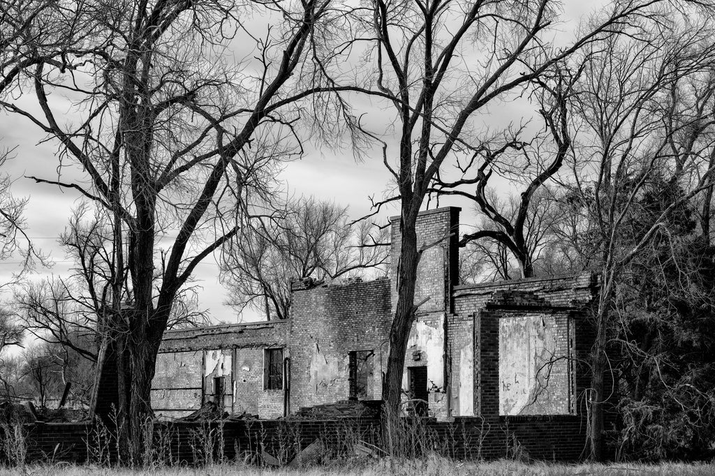 Black and white photograph of the burned ruins of a long abandoned school built by the WPA in the 1930s in the farming community of Hext, Oklahoma.