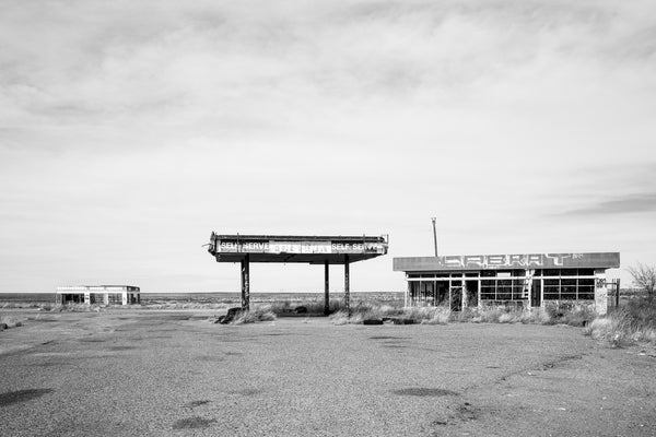 Black and white photograph of abandoned gas station buildings in the wide open Texas Panhandle.