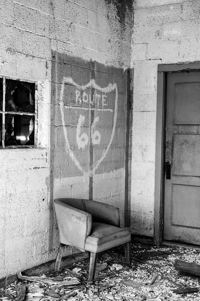Black and white photograph of an old chair inside an abandoned motel found along a forgotten stretch of old Route 66 in Texas.