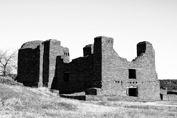 Black and white photograph of a massive, historic stone ruin in the New Mexico high desert landscape. These are the remains of the long-abandoned Quarai Mission built by the Spanish in the 1600s.