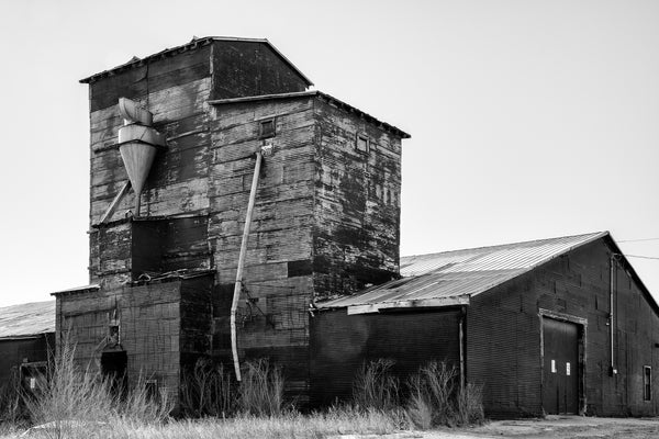 Black and white photograph of an old corrugated metal grain elevator building in New Mexico.
