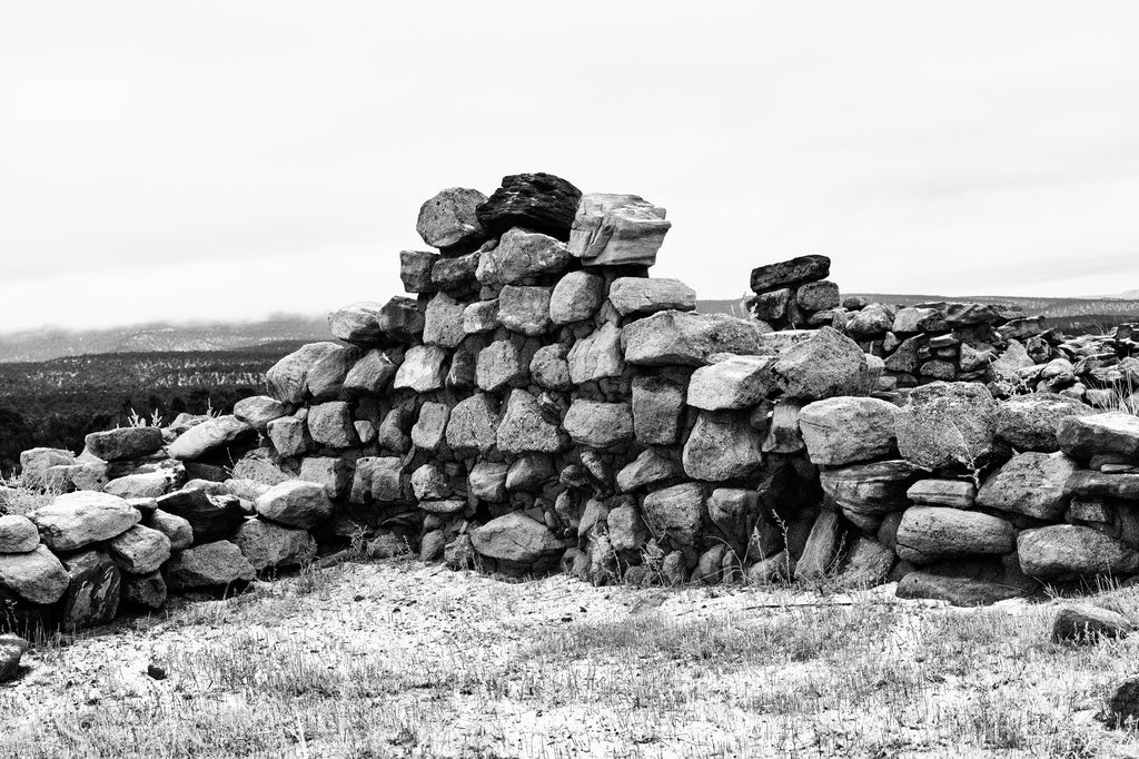 Black and white landscape photograph of very old stone ruins in the mountains of northern New Mexico. 