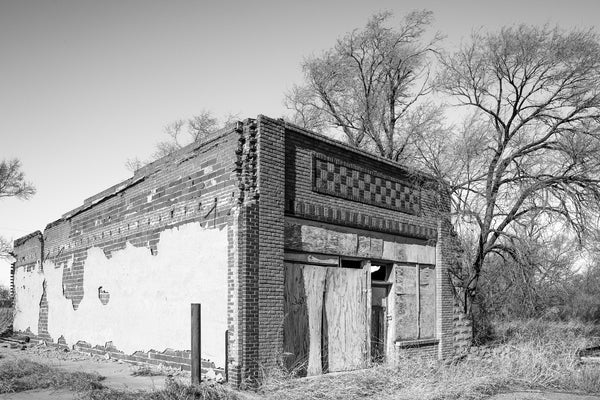 Black and white photograph of an abandoned building in a ghost town on old Route 66 in Oklahoma. Constructed prior to 1905, it housed a general merchandise store and grocer.