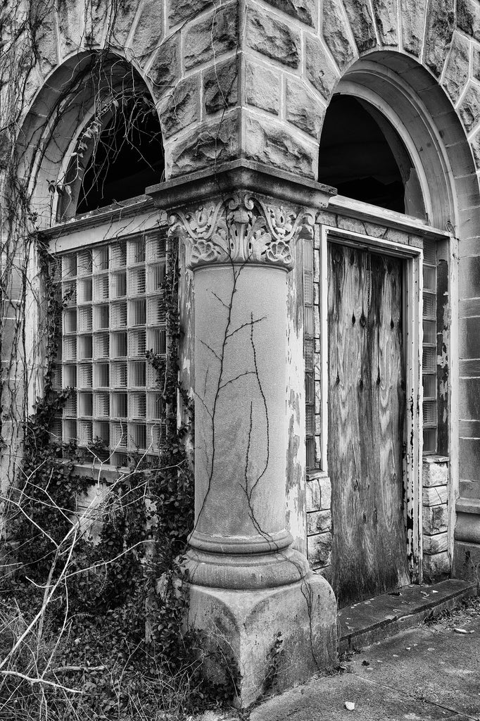 Black and white photograph of an ornate corner column that's part of an abandoned commercial building in a small Midwestern town.