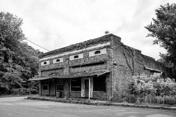 Black and white photograph of abandoned historic storefronts in a very small southern railroad town