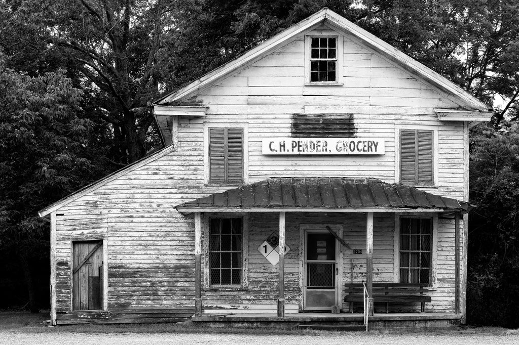 Black and white photograph of the historic C.H. Pender Grocery Store building located at a crossroads in rural North Carolina. The structure was built in the 1880s with a later addition on the side to serve as a post office. 