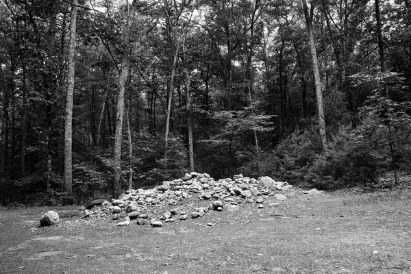 Black and white photograph of the pile of stones left by 150 years of visitors to Thoreau's cabin site in the woods at Walden Pond in Concord, Massachusetts.