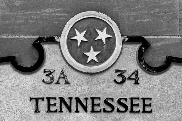 Black and white detail photograph of a Tennessee state historical marker in Nashville featuring the Tennessee Tri-Star logo and the word "Tennessee."