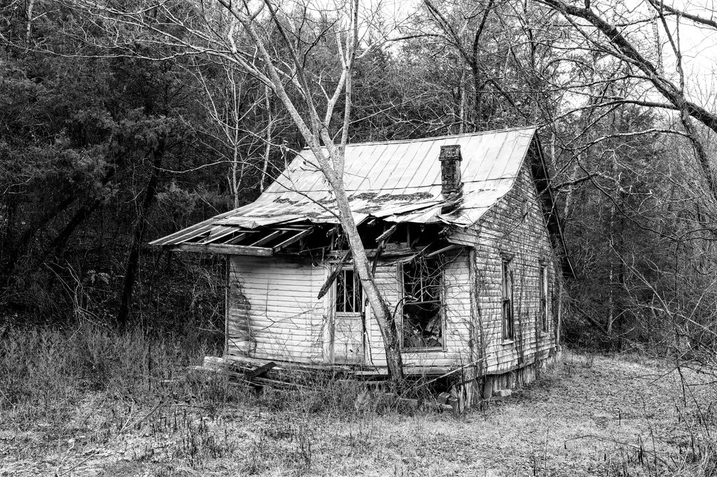 Black and white photograph of an abandoned old farmhouse found along a backroad in the American South.