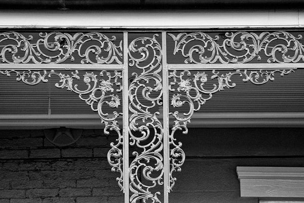 Black and white architectural detail photograph of iconic, decorative balcony ironwork flourishes in the French Quarter of New Orleans. New Orleans is famous for its romantic balconies with their fanciful ironwork railings.
