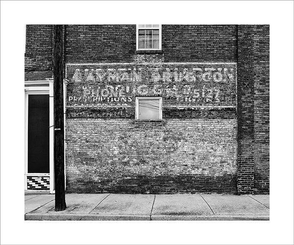 Black and white photograph of layers of peeling painted ads on the side of an old pharmacy building in South Nashville.  This photograph can be seen in the Nashville Room, a private dining room at Nashville's amazing Prima Restaurant in the Gulch neighborhood. At 16" x 20," this is the exact size and finish as the print at Prima -- just add your own top mat and framing.