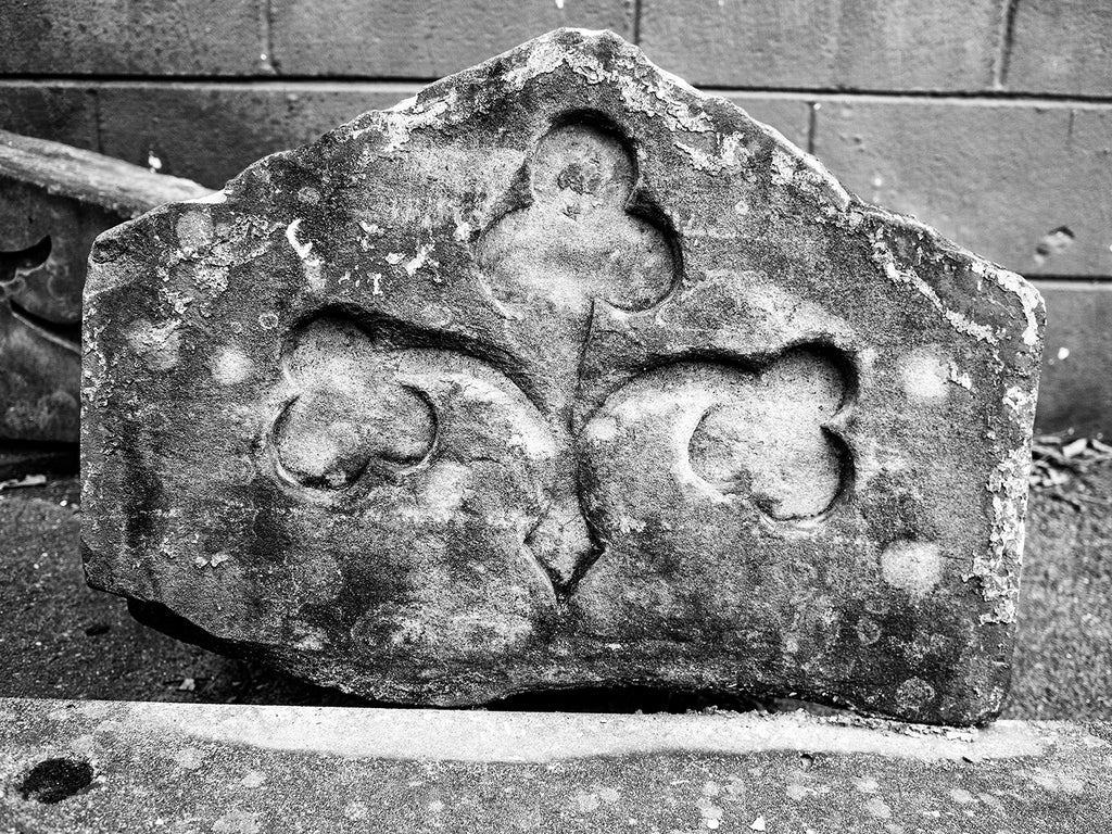 Black and White Photograph of a broken Carved Stone Architectural Fragment with Shamrock Design