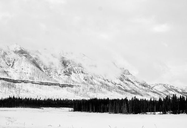 Black and white winter landscape photograph of cloudy Wyoming mountains in snow.